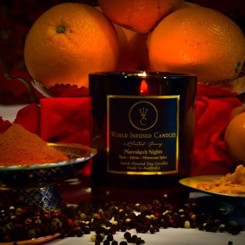 Marrakech Nights Soy Candle lit with spices in the foreground. the background is filed with citrus fruits and rose petals