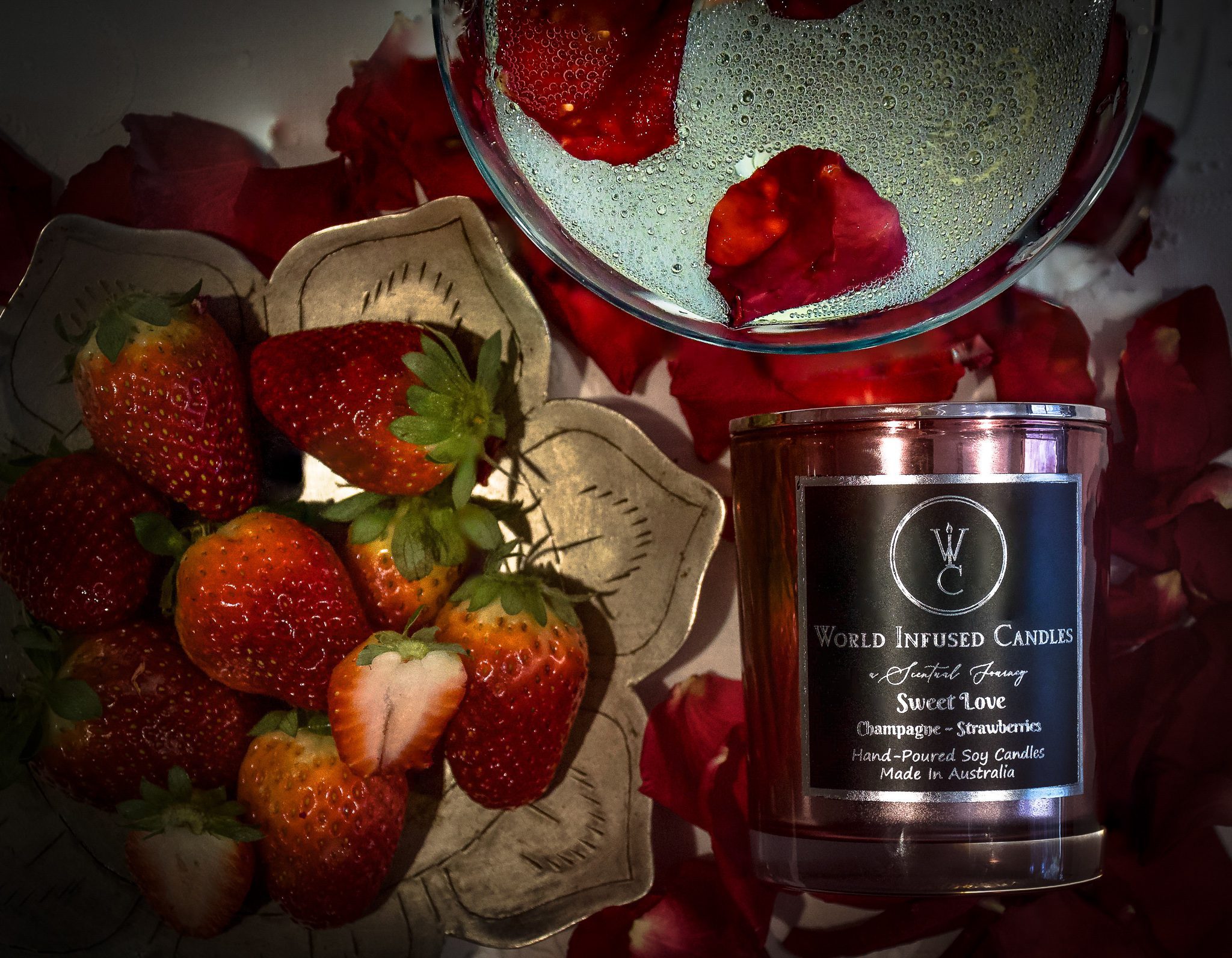 Top down shot of Sweet Love soy candle with a glass of champagne and strawberries surrounding the scene